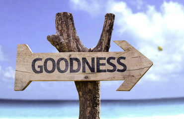 Goodness wooden sign with a beach on background