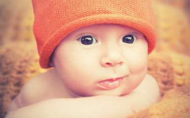 cute newborn baby in knitted orange hat cap