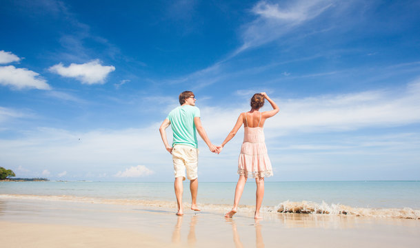back view of couple walking at tropical beach