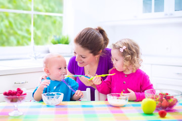 Obraz na płótnie Canvas Young mother and kids having breakfast