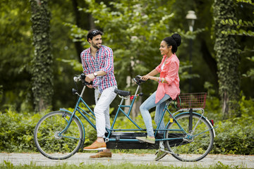 Young couple riding on the tandem bicycle