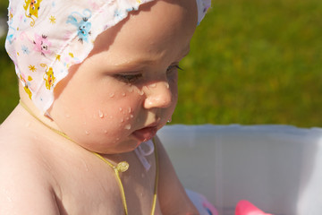 Little girl bathes in a basin on the nature