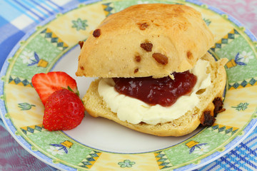 Scone with strawberry jam and clotted cream, close up