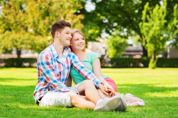 smiling couple sitting on grass in park
