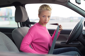Beautiful woman fastening seat belt.