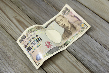 ten thousand yen banknotes on wooden background