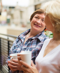 Two women drink tea on balcony