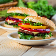 homemade hamburger with fresh vegetables on cutting board