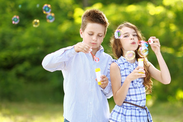 Portrait of a boy girl in a summer with bubble