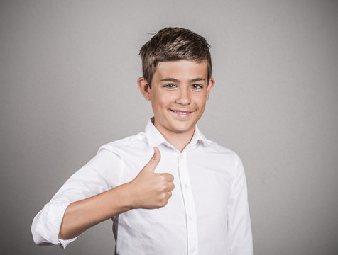 Teenager giving thumbs up gesture on grey background 