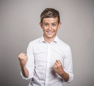 Happy teenager celebrating success, grey wall background 