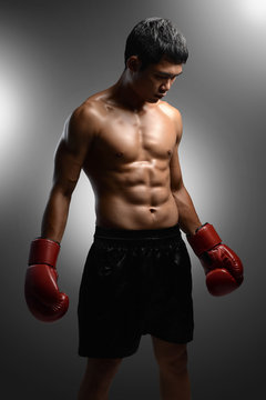 boxer with boxing gloves standing on grey background with spotli