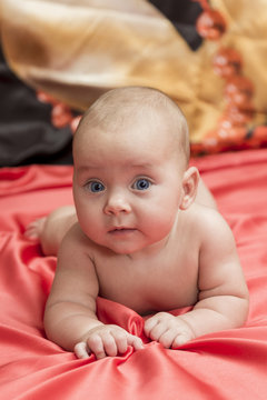 Baby on red bedsheets