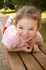 Kid lying on wooden park bench