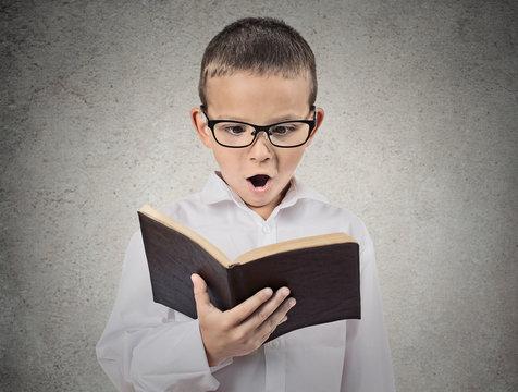 Surprised boy reading book, isolated grey wall background 