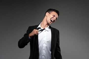 Man loosing tie on grey background.