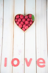 fresh raspberries in heart shape basket on kitchen table