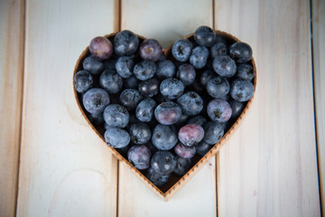 fresh blueberries in heart shape basket on kitchen table