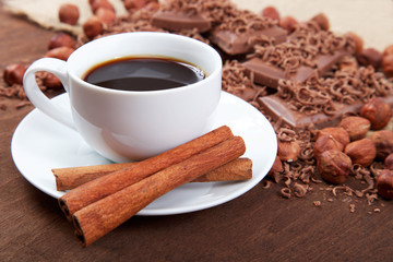 Cup of coffee with cinnamon sticks in a saucer, chocolate and ha