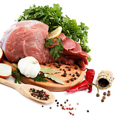 Raw meat, vegetables and spices on a wooden cutting board.