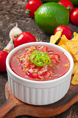 Mexican nacho chips and salsa dip in bowl on wooden background