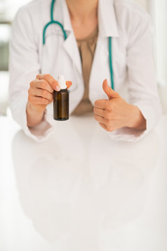 Closeup on doctor woman showing medicine bottle and thumbs up