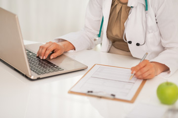 Closeup on doctor woman working on laptop in office