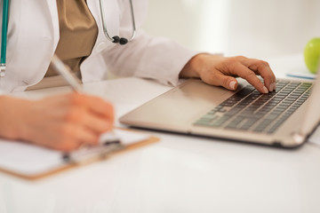 Closeup on doctor woman working on laptop in office