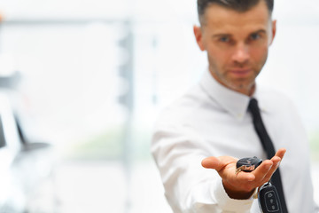 Car Salesman Giving Key of New Car at Showroom