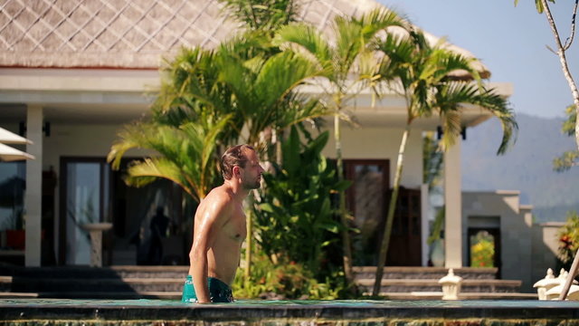 Man walk out of luxury swimming pool and dry with towel