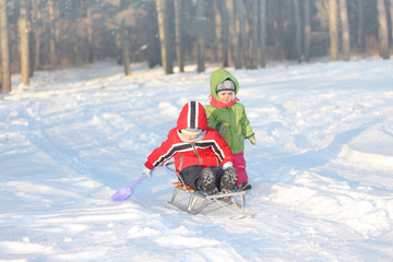 Children play on a sled in the snow