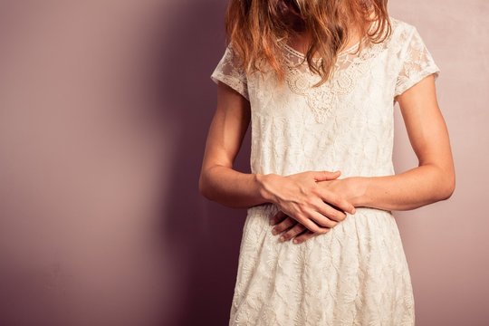 Young woman in white dress with stomach pains