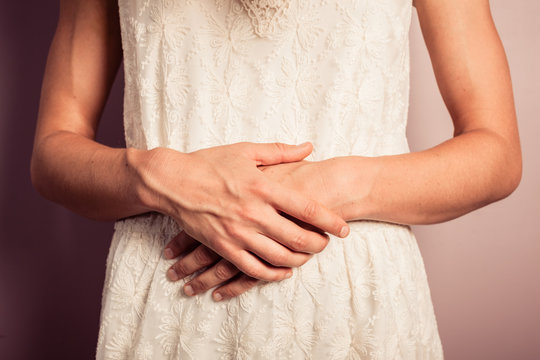 Young woman in white dress with stomach pains