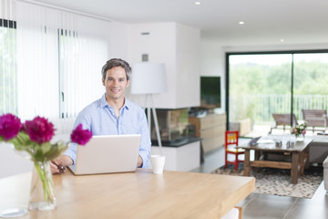 attractive man is using a laptop at home