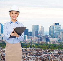 smiling businesswoman in helmet with clipboard