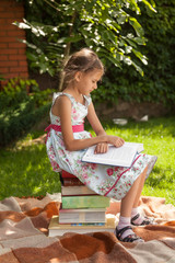 Naklejka premium smart girl reading big book at park at sunny day