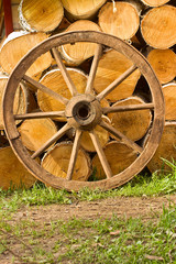 Fototapeta na wymiar Old wagon wheel on a background of wood