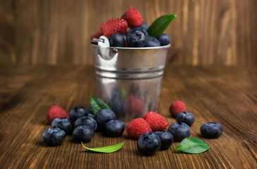 blueberries and raspberries in a small bucket