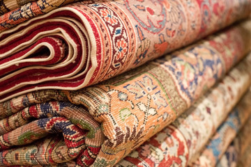 Bright various oriental rugs and carpets stacked for display.