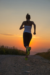 Plakat woman running on a mountain road at summer sunset