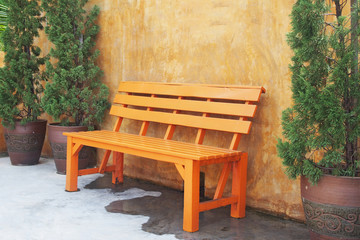 orange wooden bench against concrete wall