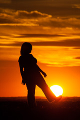 Silhouette of a woman against the sky at sunset