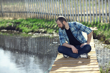 man meditating on the bank of a pond