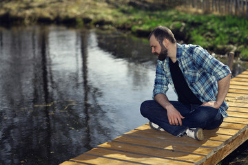 Fototapeta premium man meditating on the bank of a pond