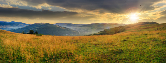 valley in mountains  on hillside under sky with clouds at sunset