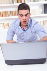 shocked student sitting in library looking at computer monitor