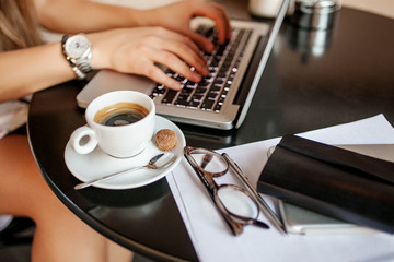 Young business woman in cafe drinking coffee with laptop