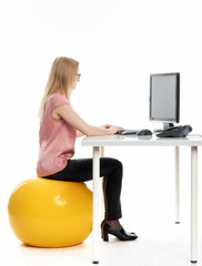 Geschäftsfrau mit Sitzball am Schreibtisch