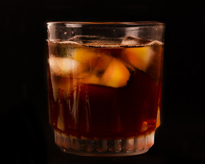 glass with dark liquid full with ice cubes on white background