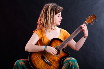 Young girl with dreadlocks playing guitar